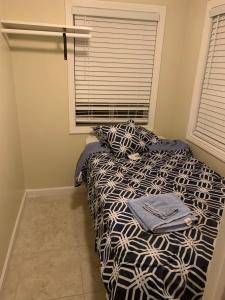 a bed with a black and white comforter and a window at Sky Fresh Home Stay in Apple Valley