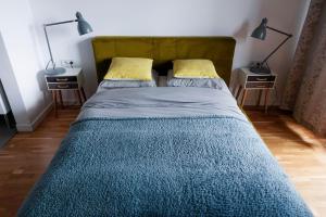 a bed with a blue comforter and two night stands at Arena Studio in Krakow