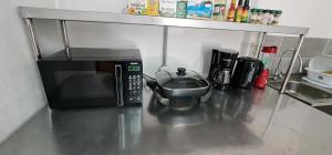 a kitchen counter with a microwave and a tea pot at Sleep&Go! Cabina Cuadruple en Siquirres Centro -and rafting tour! in Siquirres