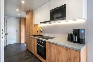 a kitchen with white cabinets and a black appliance at Recreatiepark Maas en Bos in Wellerlooi +22 photos