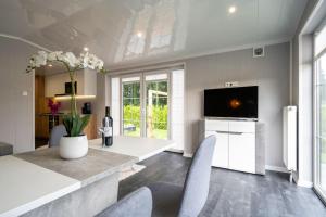 een woonkamer met een tafel en stoelen en een televisie bij Recreatiepark Maas en Bos in Wellerlooi