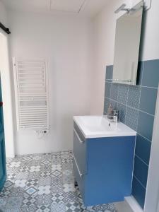 a bathroom with a white sink and blue tiles at Moana in Honfleur