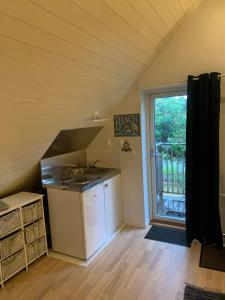 an attic kitchen with a sink and a window at Mysigt rum i villa med egen ingång och nära havet. in Åhus