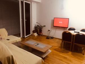 a living room with a table and a flat screen tv at Bisera in Skopje