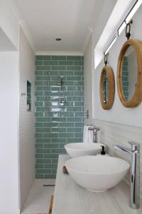 a bathroom with two sinks and a green wall at Seafront house with a view in Kleinmond