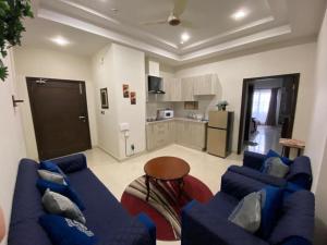ein Wohnzimmer mit blauen Sofas und eine Küche in der Unterkunft The River View Apartment in Rawalpindi