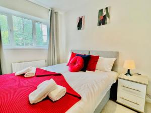a bedroom with a bed with red and blue pillows at 3 bedroom lovely apartment in Slough with free parking in Farnham Royal