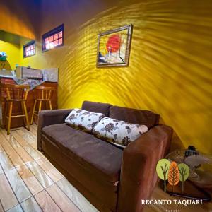 a living room with a couch and a yellow wall at Recanto Taquari - Praia e cachoeira in Paraty