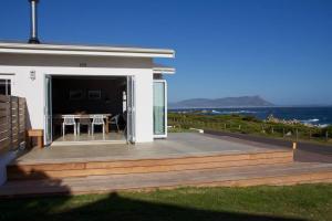 a house with a wooden deck with a table at Seafront house with a view in Kleinmond