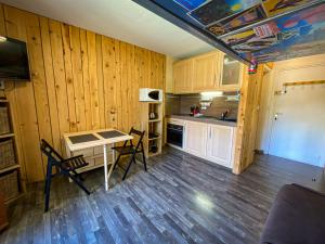 een keuken met houten wanden en een tafel en stoelen bij Studio balcon vue Alpes pistes de ski à 5 min in Saint-Étienne-de-Tinée