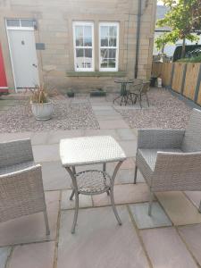 a patio with two chairs and a table and chairs at No 2 New Buildings Morebattle in Morebattle