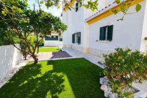 a yard with green grass and a white house at Azeitao Idílica Moradia T4 no Descanso do Campo in Setúbal