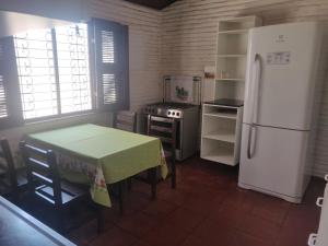 uma cozinha com uma mesa e um frigorífico branco em Casa no Porto das Dunas Com Vista pro mar em Aquiraz