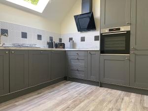 a kitchen with gray cabinets and a flat screen tv at Fabulous 2 Bedroom House just outside Edinburgh in Auchendinny