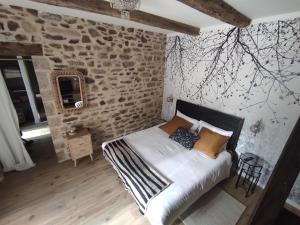 une chambre avec un lit dans un mur de briques dans l'établissement La Ville Es Riez Chambre d'hôtes, à Corseul