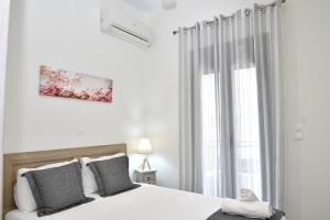 a white bedroom with a bed and a window at Michaela's guesthouse in Nafplio