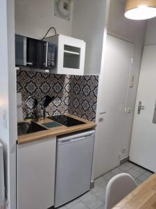 - une cuisine avec un évier et un comptoir dans l'établissement Petit Appartement Cosy, à Chaville