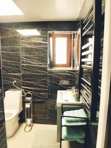 La salle de bains est pourvue de carrelage noir, d'un lavabo et de toilettes. dans l'établissement Studio - WIFI - Train Station - Love Bridgi home, à Forbach