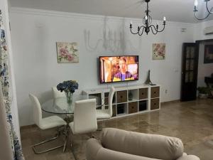 sala de estar con TV, mesa y sillas en Alojamiento las Delicias, en Hornachuelos