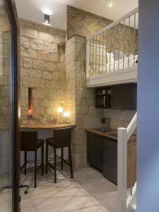 a kitchen with a table and chairs and a stone wall at Le Lodge de Richard, studio indépendant in Marçay