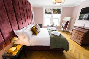 a bedroom with a large bed with a red wall at Dragon Villas by Maison Parfaite - Luxury Studios & Apartments - Harrogate in Harrogate