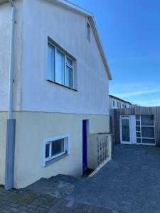 a white building with two windows and a driveway at The Little Guesthouse Downtown - Keflavik Airport in Keflavík