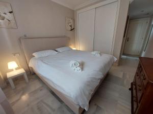 ein Schlafzimmer mit einem weißen Bett und Handtüchern darauf in der Unterkunft La Palmera - Amazing apartment with excellent location & views in Marbella