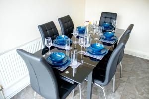 a table with black chairs and blue plates and glasses at Spacious 5-Bed House! Tilbury! Free parking! in Tilbury