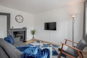 a living room with a couch and a clock on the wall at Carlile House - London 5 bedroom Free Parking & Garden by Damask Homes in London