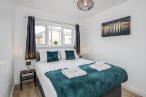 a bedroom with a large bed with two towels on it at Carlile House - London 5 bedroom Free Parking & Garden by Damask Homes in London