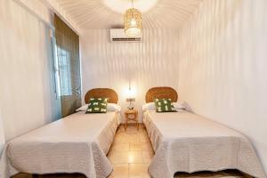 two beds in a room with white walls at Apartamento Ronda Genil con parking gratuito in Granada