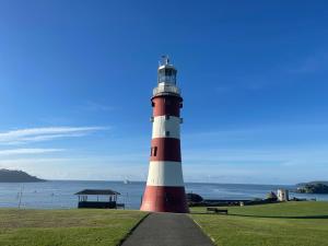 um farol vermelho e branco ao lado do oceano em Plymouth Barbican boutique luxury Apartment em Plymouth