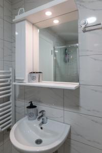 a white bathroom with a sink and a mirror at Apartman Agin Kutak in Bajina Bašta