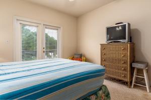 ein Schlafzimmer mit einem Bett und einem TV auf einer Kommode in der Unterkunft Dunes East - 330 Audubon Unit B home in Dauphin Island