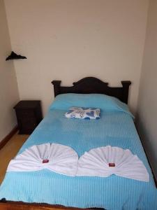 Una cama azul con dos toallas blancas. en Pueblito viejo, tu casa por días o temporadas en Zapatoca