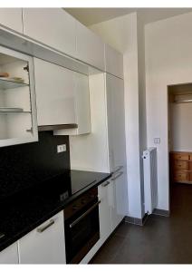 cocina con armarios blancos y encimera negra en Studio apartment in center Brno en Brno