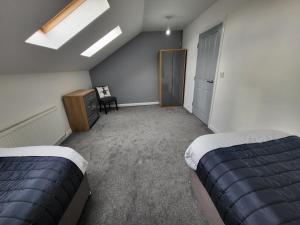 sypialnia na poddaszu z 2 łóżkami i świetlikiem w obiekcie Immaculate 7 Bed House in Ashton-under-Lyne OL7 w Manchesterze