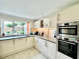 a kitchen with white cabinets and a large window at 3 bedroom house with ample parking and garden 