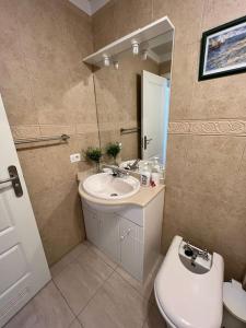 a bathroom with a sink and a toilet and a mirror at Ocean view apartment in Golf del Sur in San Miguel de Abona