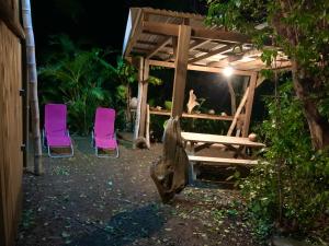 a wooden pergola with two chairs and a table at LODGE COLIBRIS vue panoramique mer et montagne pelée , 500 m plage dans un parc , Calme assuré Idéal pour découvrir le nord Caraïbes in Le Carbet