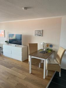ein Esszimmer mit einem Tisch und einem TV in der Unterkunft Hanseatenhaus App. 40 in Westerland