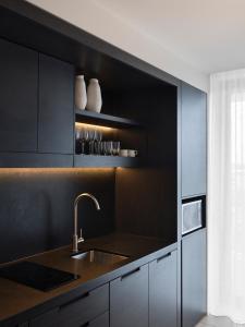 a kitchen with black cabinets and a sink at Burbury Hotel in Canberra