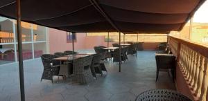 un comedor con mesas y sillas bajo una sombrilla en maison familiale chez Salwa, en Ouarzazate
