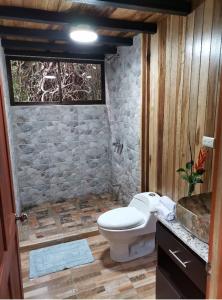 a bathroom with a toilet and a stone wall at Tree houses Bosque Nuboso Monteverde in Monteverde Costa Rica