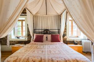 um quarto com uma cama de dossel e almofadas cor-de-rosa em R3 Service - Quinta da Melroa - Mountain Villa em Viseu