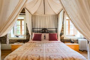 a bedroom with a canopy bed with pink pillows at T3 Quinta da Melroa - Mountain Villa - Caramulo in Viseu