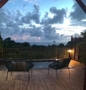 eine Terrasse mit 2 Stühlen und einem Pool bei Sonnenuntergang in der Unterkunft Héritage créole 1 in Sainte-Luce