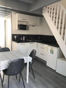 een keuken met een tafel en stoelen en een trap bij Petite maison avec piscine à 500m de la plage in Guidel