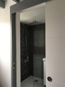 een badkamer met een douche en een glazen deur bij Petite maison avec piscine à 500m de la plage in Guidel
