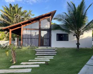 a house with a green yard with a stone path at Chalé Litoral Norte - em condomínio de praia in Camaçari